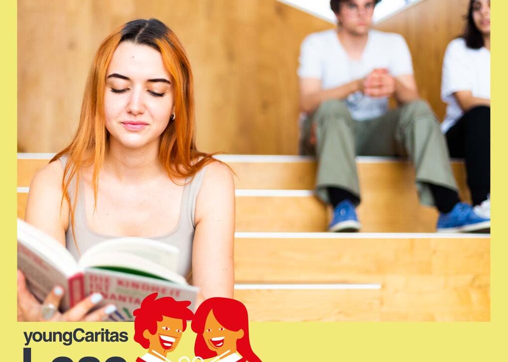 Eine junge Frau sitzt auf Stufen und liest ein Buch, während andere im Hintergrund sind, was eine entspannte Lernatmosphäre zeigt.