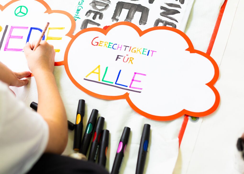 Detailaufnahme eines Papiers mit der Aufschrift 'Gerechtigkeit für Alle'. Es sind auch farbige Marker sichtbar.