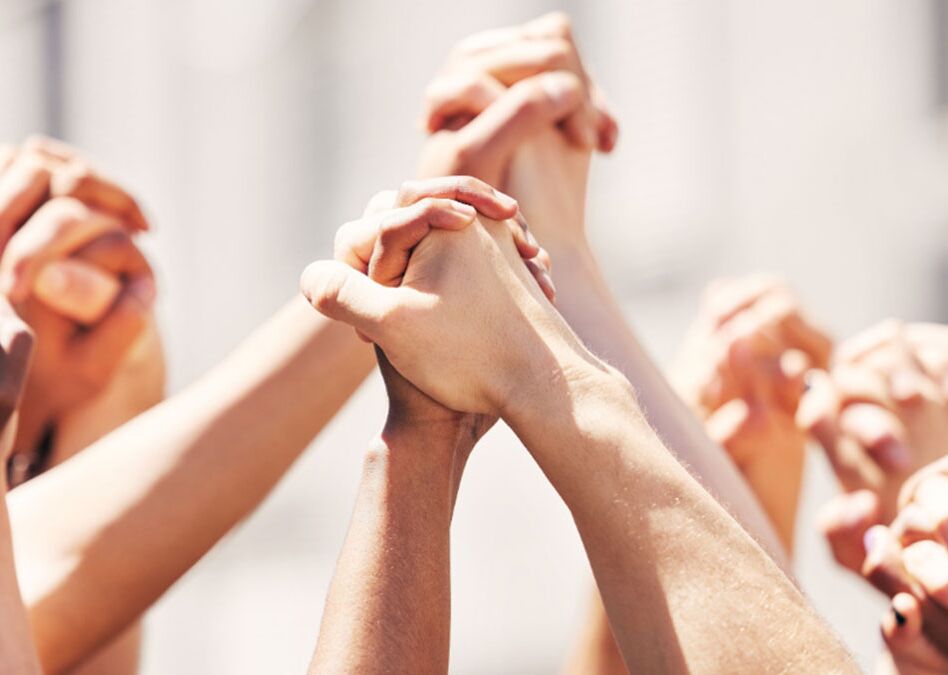 Eine Gruppe von Händen unterschiedlicher Hautfarben, die sich zusammenfügen, symbolisiert Einheit und Solidarität in einem friedlichen Protest.